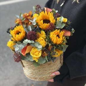 Композиция в сумке "Тональность" из подсолнухов, калл, ягод вибирнума, лимонных роз, скиммии и орхидеи в Москве