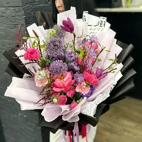 Сезонный букет с ветками магнолии, пионами и аллиумом в Москве