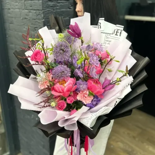 Сезонный букет с ветками магнолии, пионами и аллиумом в Москве